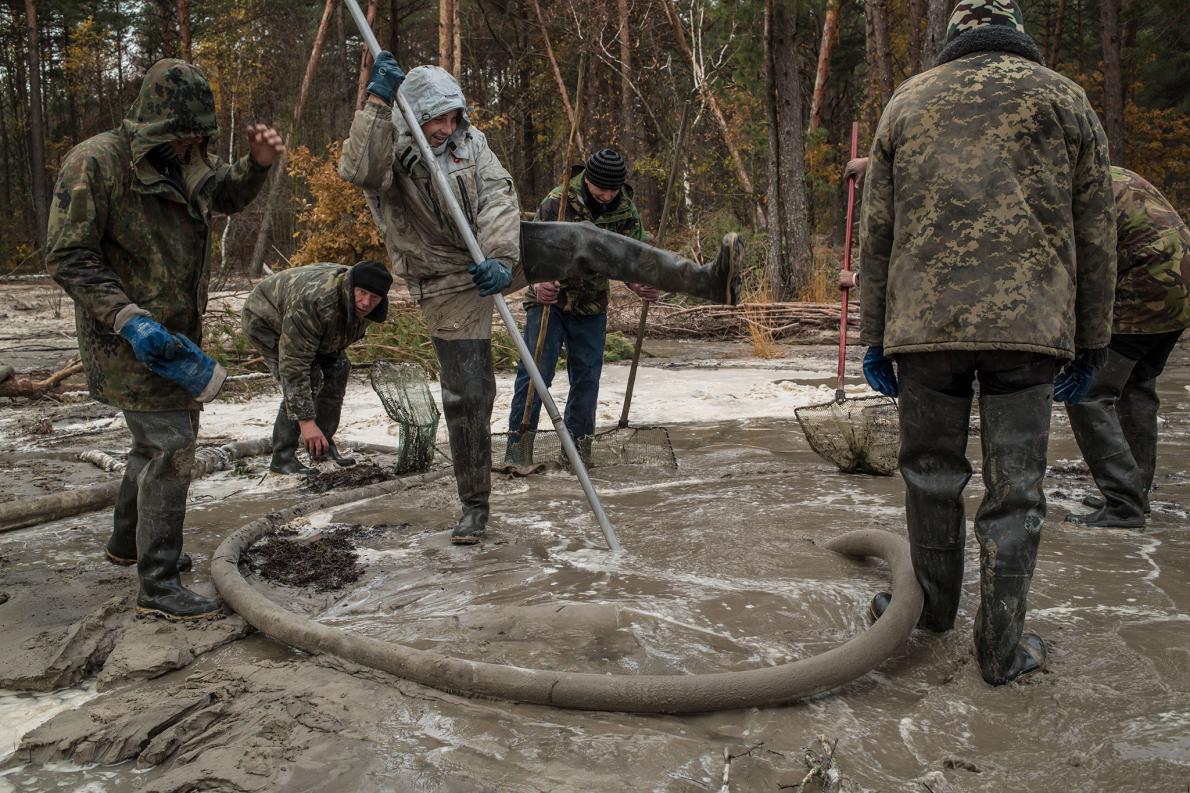 Мужчины добывают янтарь на Западной Украине в ноябре, используя воду, чтобы разрыхлить почву